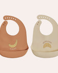 OYOY Mini Yummy silicone baby bib two pack in Caramel and Butter with food-catching pockets Banana bib and Croissant bib